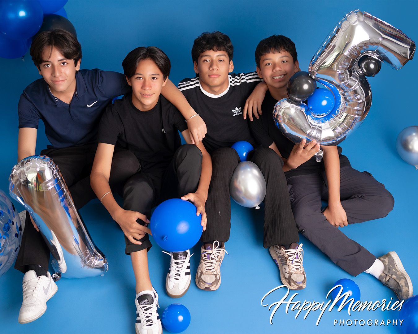 Group photo session with blue balloons and silver decorations against a blue background.
