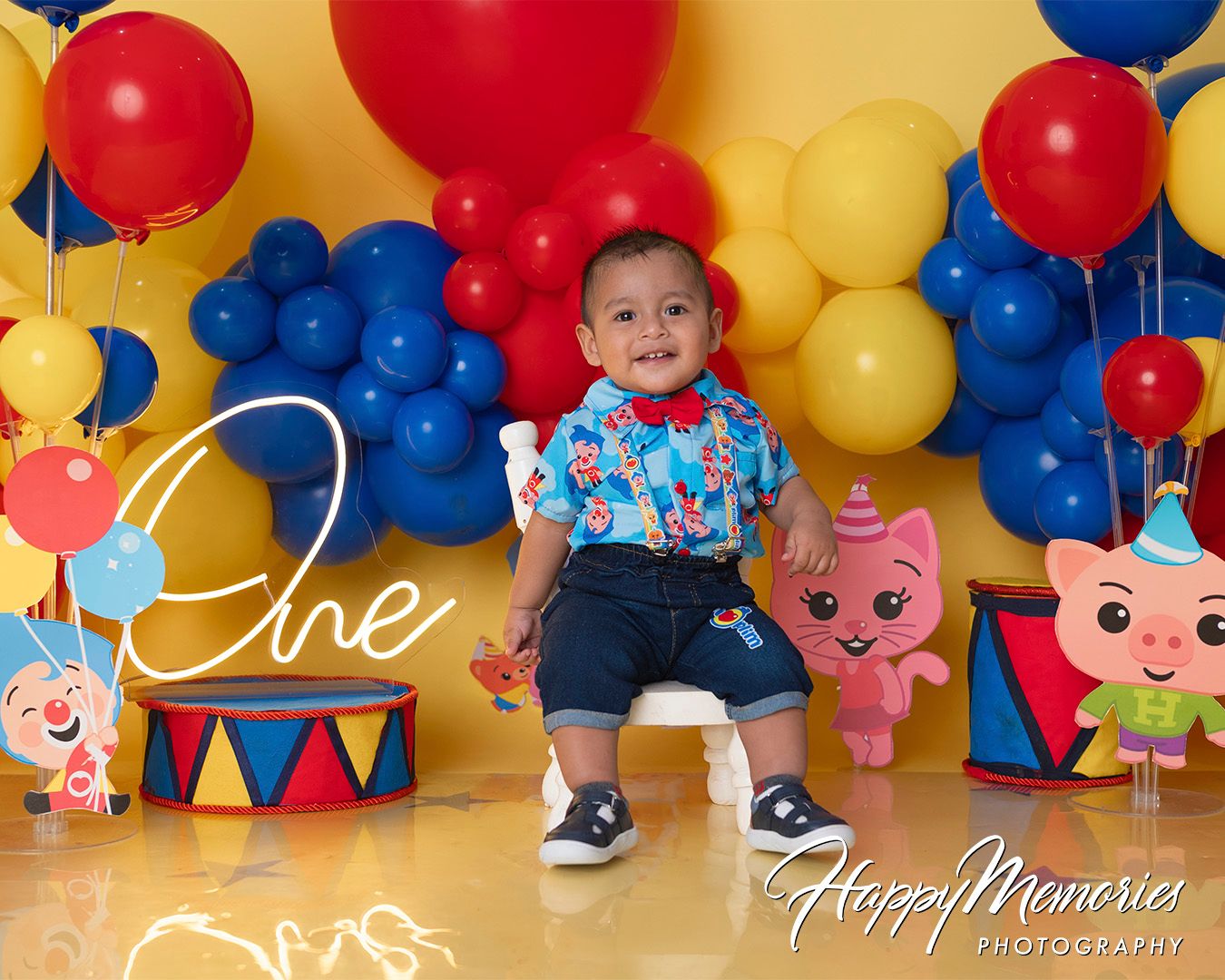 Colorful balloon arch with red, blue, and yellow balloons against a bright background with cartoon pig decorations.