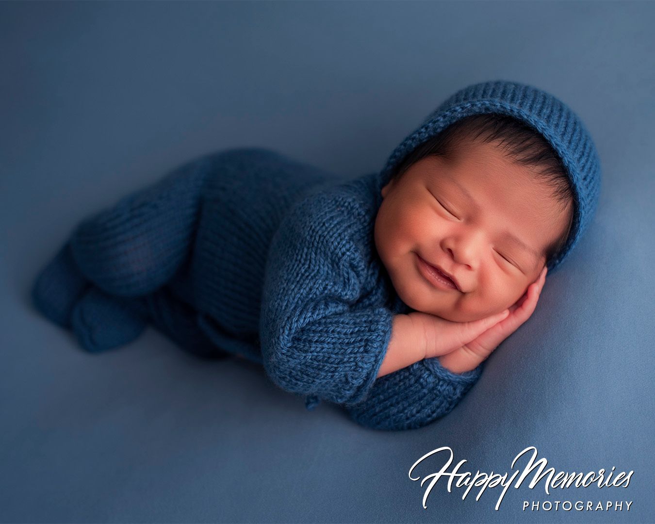 Professional newborn photography series with baby in blue wrap against navy backdrop.