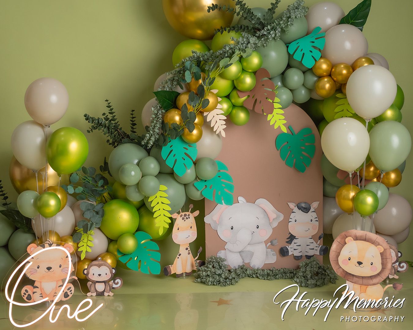 Elegant green and gold balloon arch with eucalyptus leaves creates a nature-inspired photo backdrop.