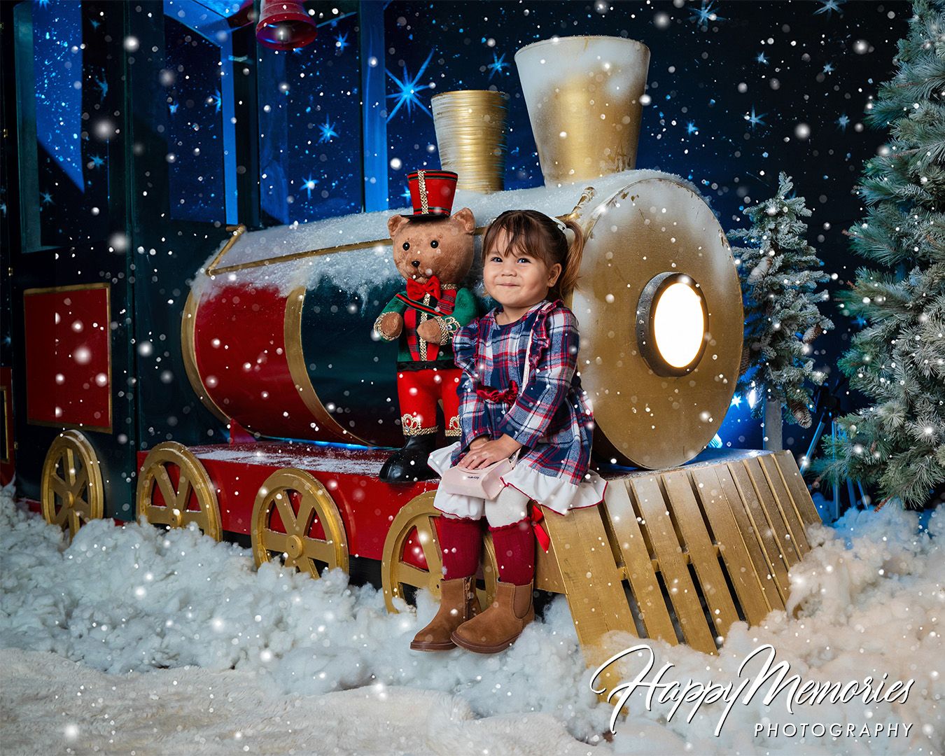 Holiday photo set with train prop and artificial snow against dark blue background.