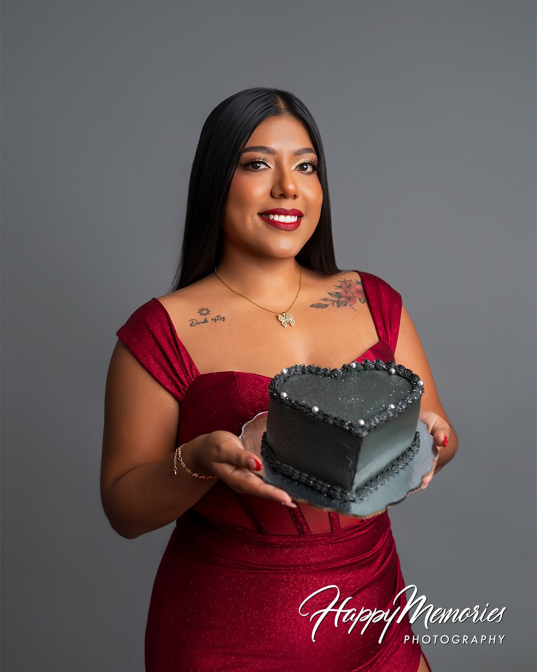 A photoshoot featuring a burgundy dress and a graduation cap against a grey background.