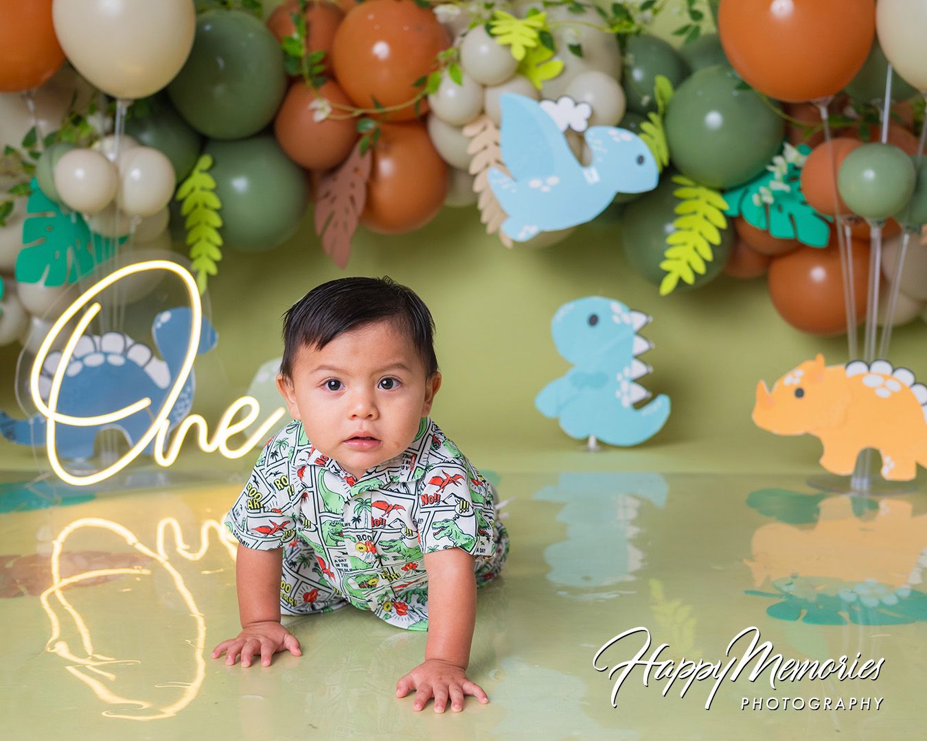 Safari-themed birthday party decor featuring orange and green balloon garland with plush animal decorations.