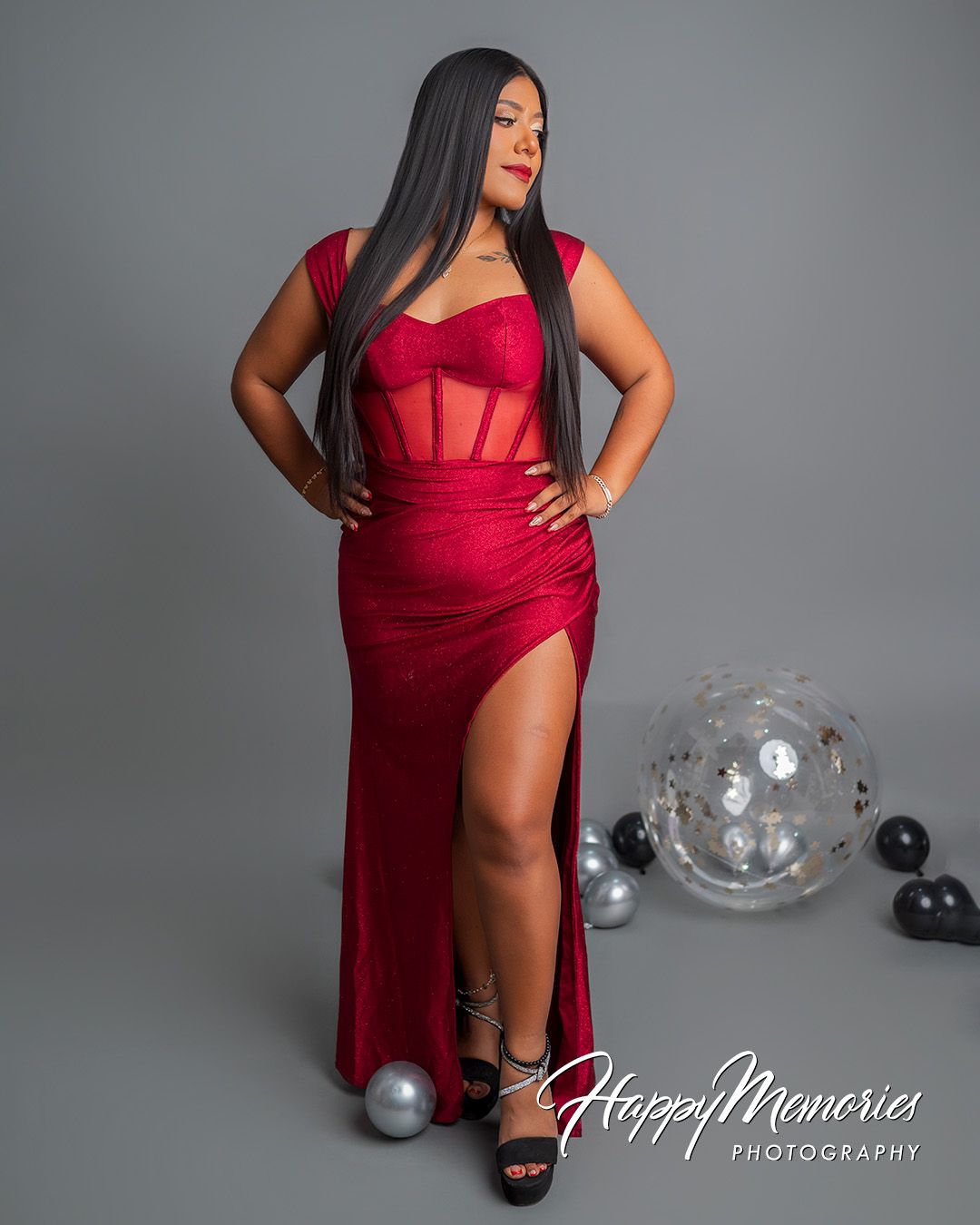 Glamorous photo shoot in red evening gown with balloon decorations.