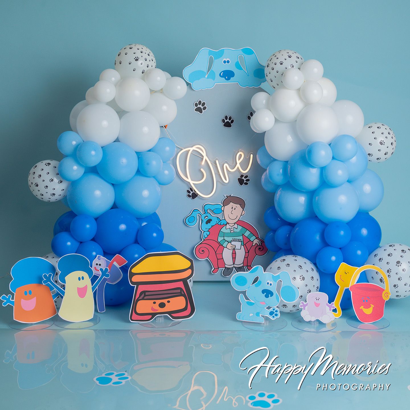 Blue's Clues themed first birthday balloon arch with blue, white, and polka dot balloons and character cutouts.