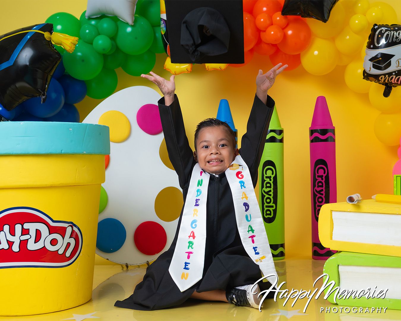 Playful graduation photos with colorful Play-Doh themed backdrop and props.