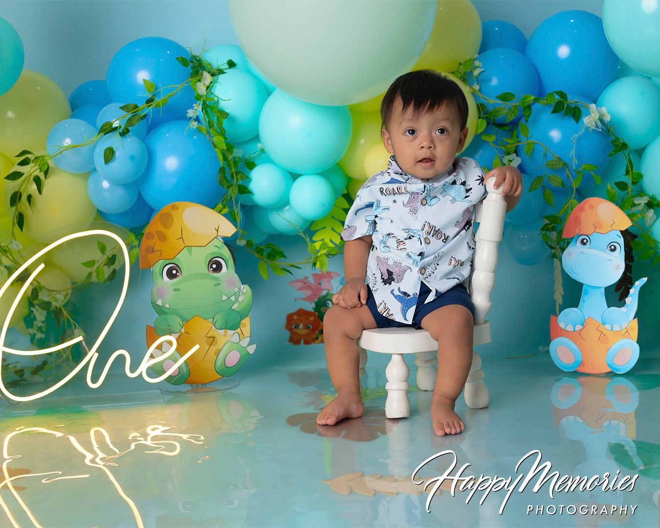 Safari-themed party backdrop with mint green balloons and tropical leaf accents.