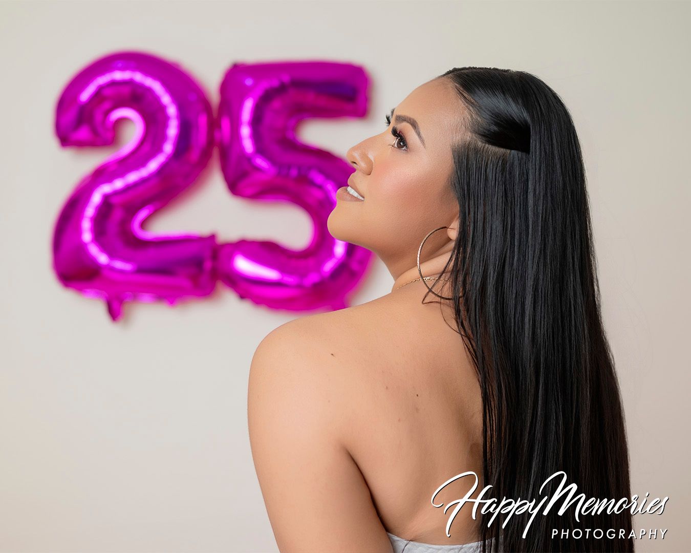 Glamour photography session with pink number balloons against white background.