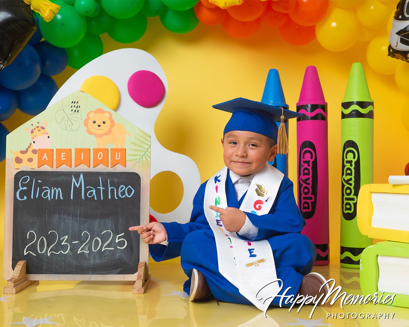 Preschool graduation photo scene with chalkboard, art supplies and festive decorations.