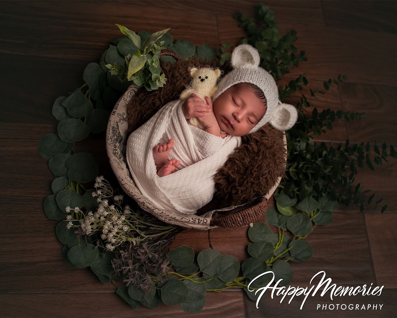 Rustic newborn photography with baby nestled in wooden bowl surrounded by greenery.