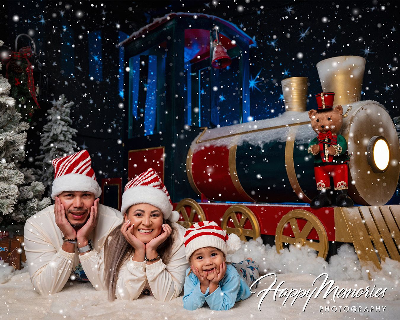 Christmas photo shoot with people lying in artificial snow with festive decorations and lighting.