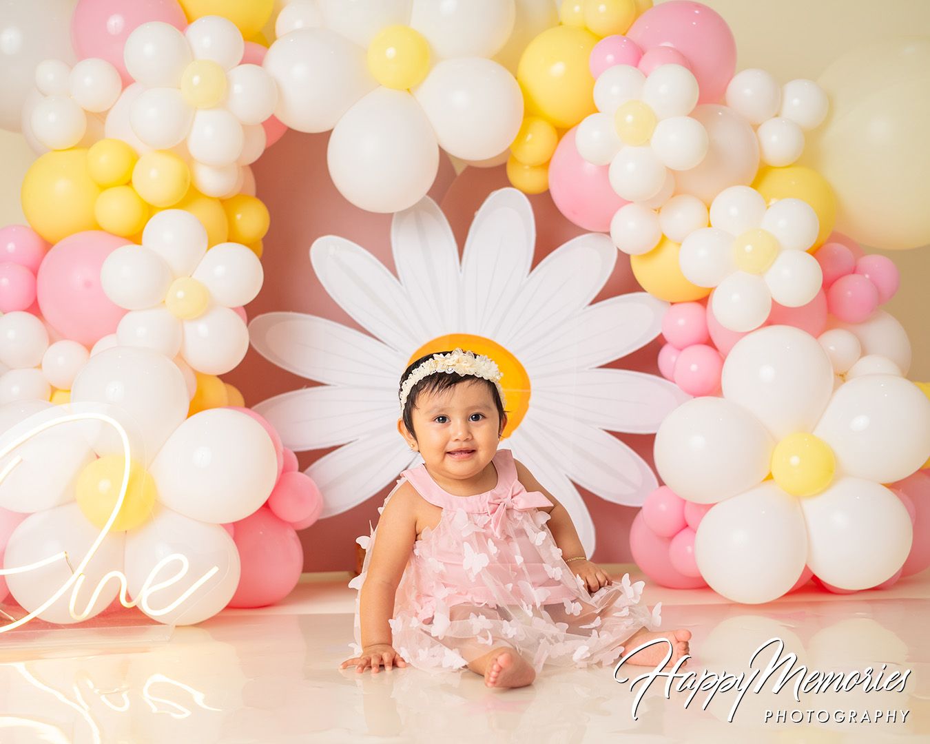 Decorative backdrop with pink and white balloons creates a soft and dreamy setting for a baby photo session.