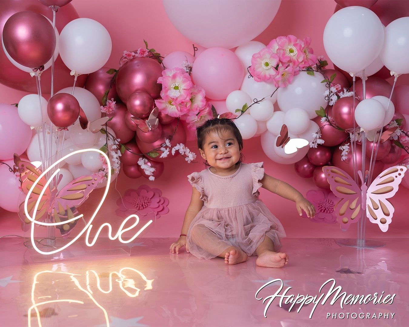 Elegant pink and white balloon arch with floral accents creates a romantic party atmosphere.