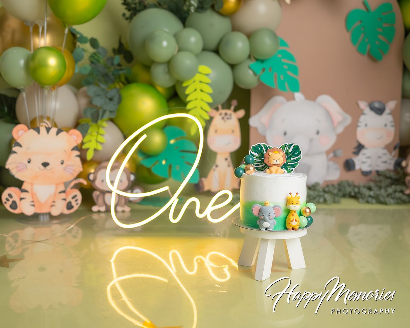 Festive party backdrop with green and yellow balloons, turquoise decorations, and whimsical cartoon animal cutouts.