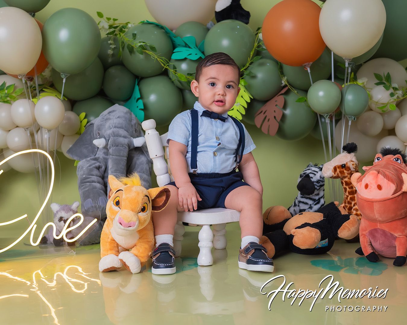 Festive safari-themed birthday setup with green and orange balloons, stuffed animals, and decorative elements.