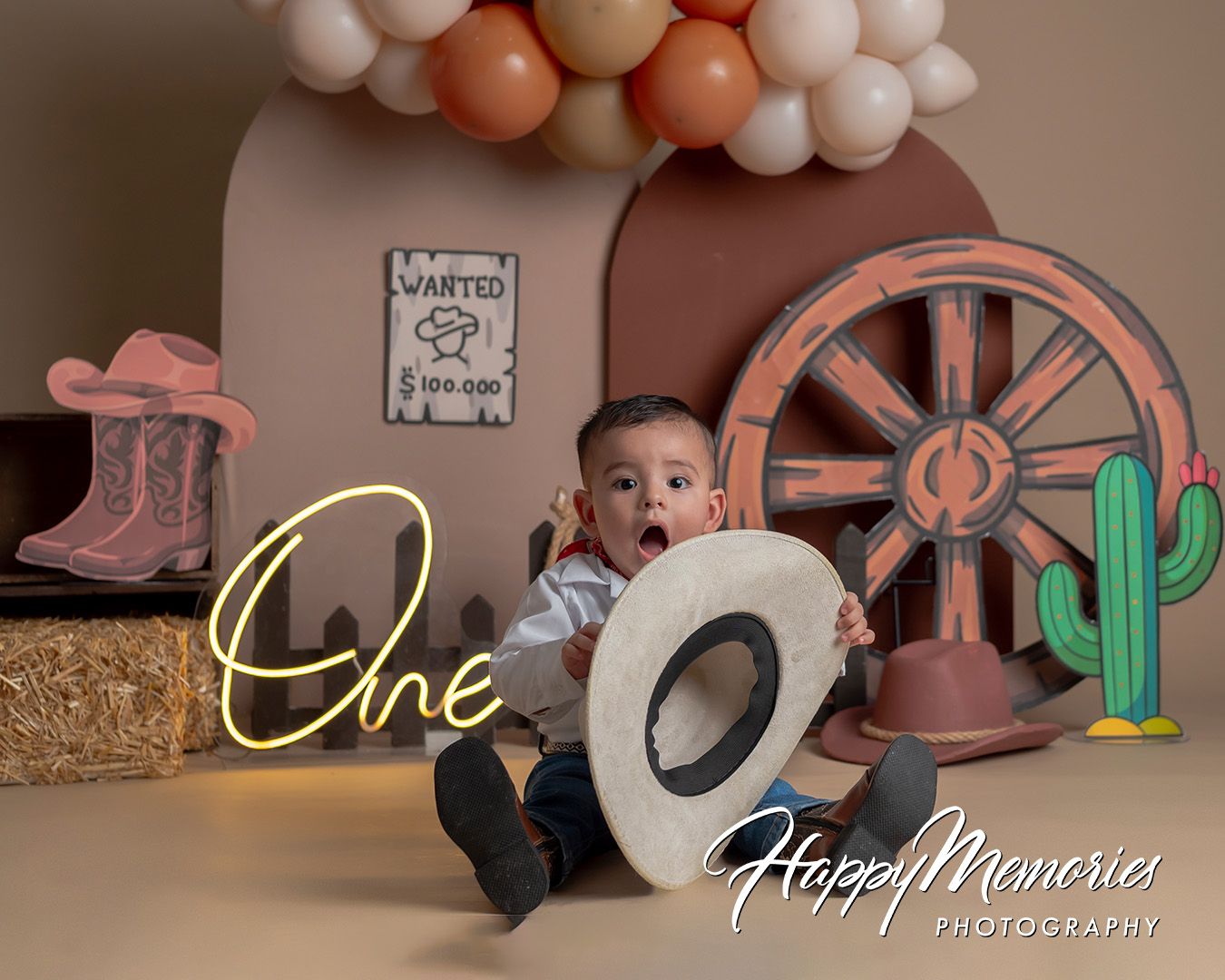 Baby boy's first birthday cowboy themed cake smash photo session with western decorations and neon One sign.