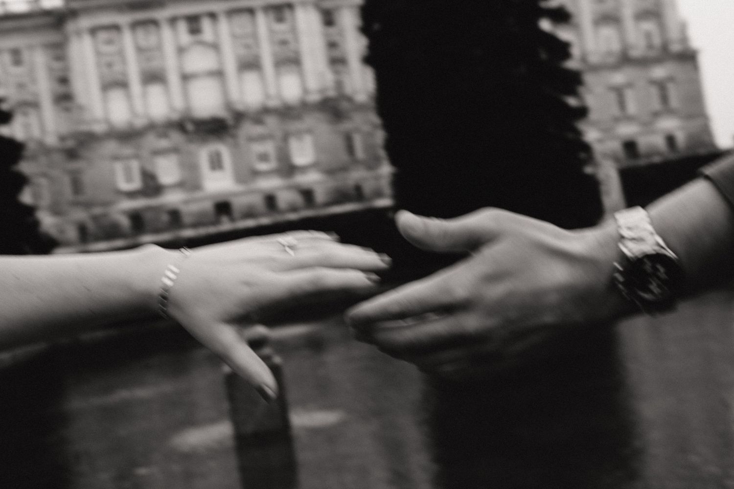 Black and white sequence showing hands passing a cigarette between two people outside a building.
