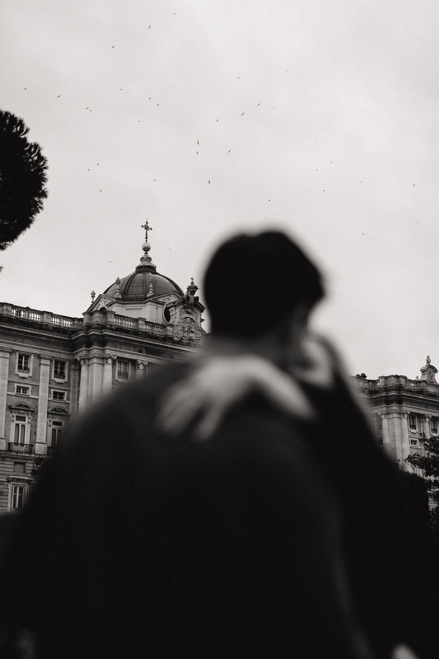 Black and white silhouettes of people against a cityscape with a domed church building visible in the background.