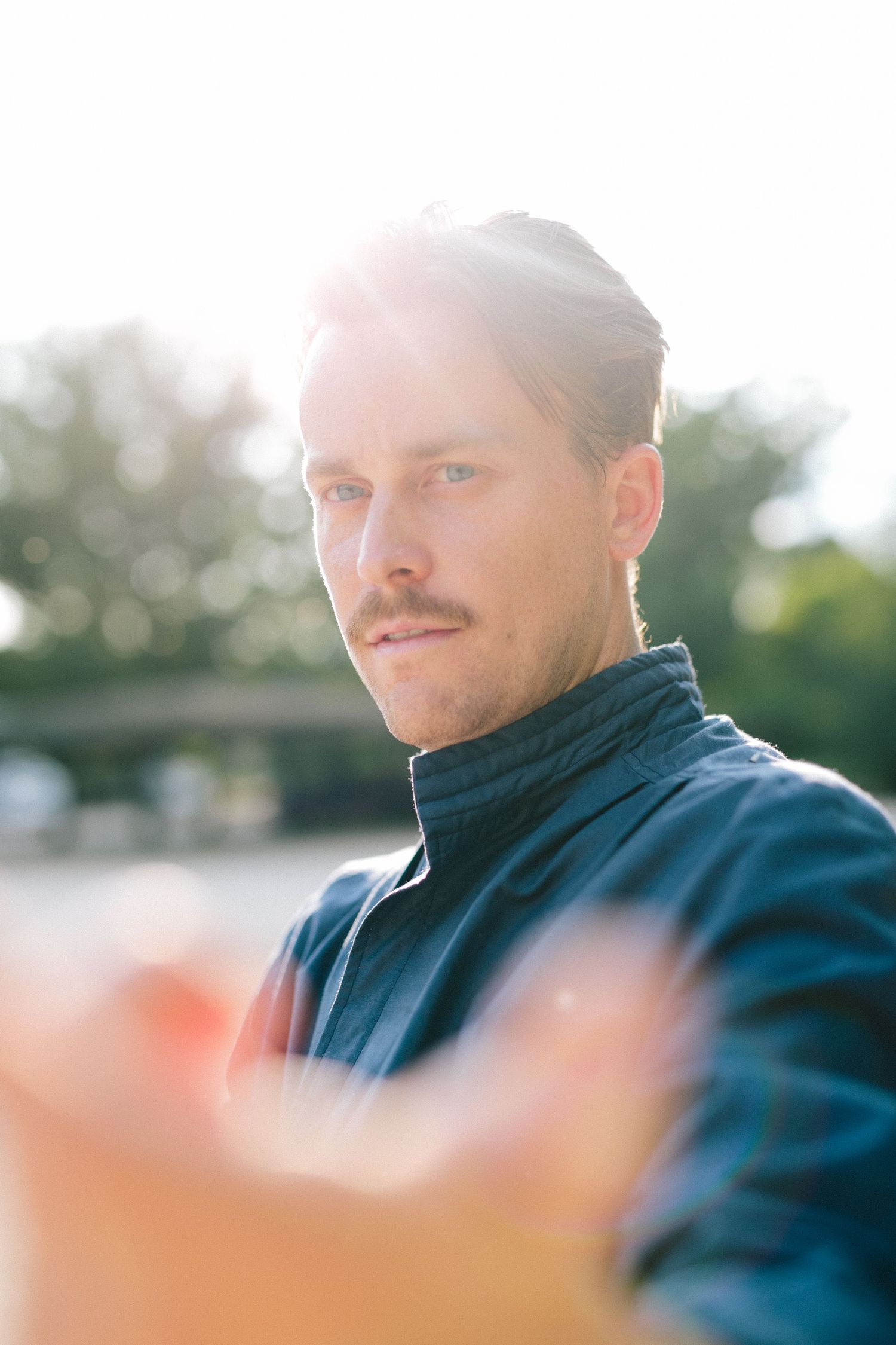 A Madrid photographer wearing a blue jacket smiles while looking at the camera in an outdoor setting with blurred background.