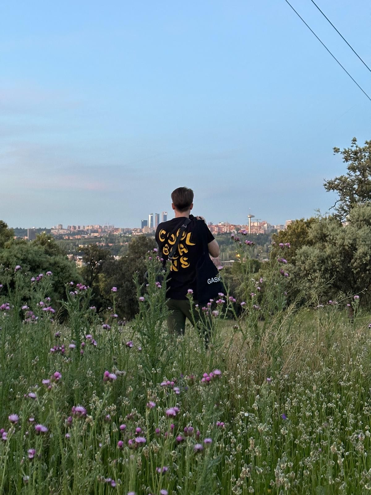 Madrid photographer stands in a wildflower meadow overlooking the Madrid city skyline during a summer sunset.