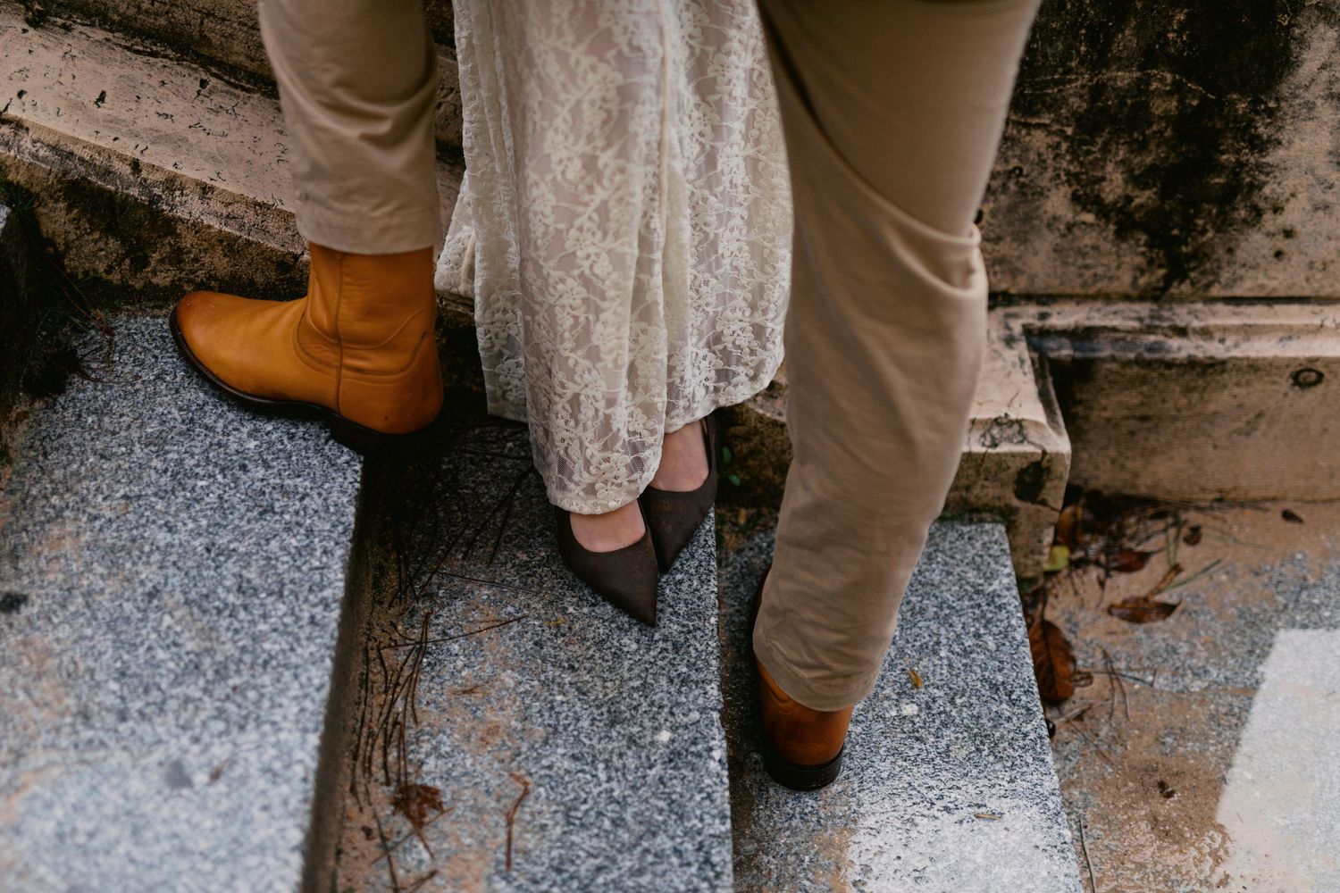 A close-up sequence of feet in brown shoes and khaki pants walking on a gravel surface.