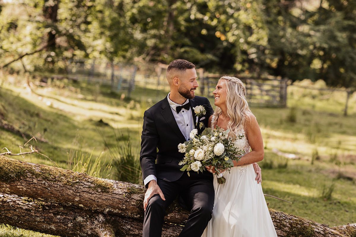 Brudpar sitter på en trästock och kramas. Romantisk stund. Parfotogarfering i skogen.