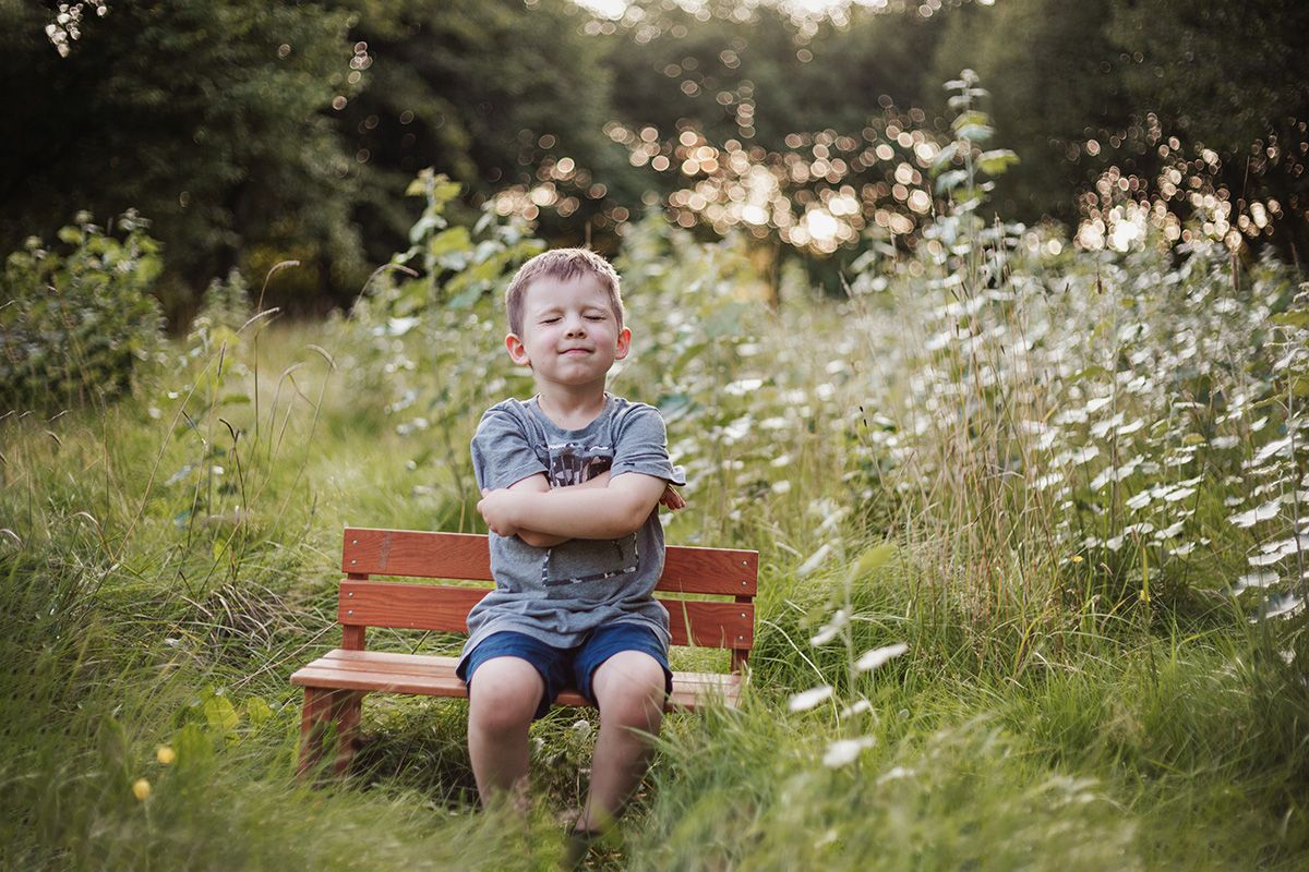 Pojke sitter på en liten bänk på sommaren.