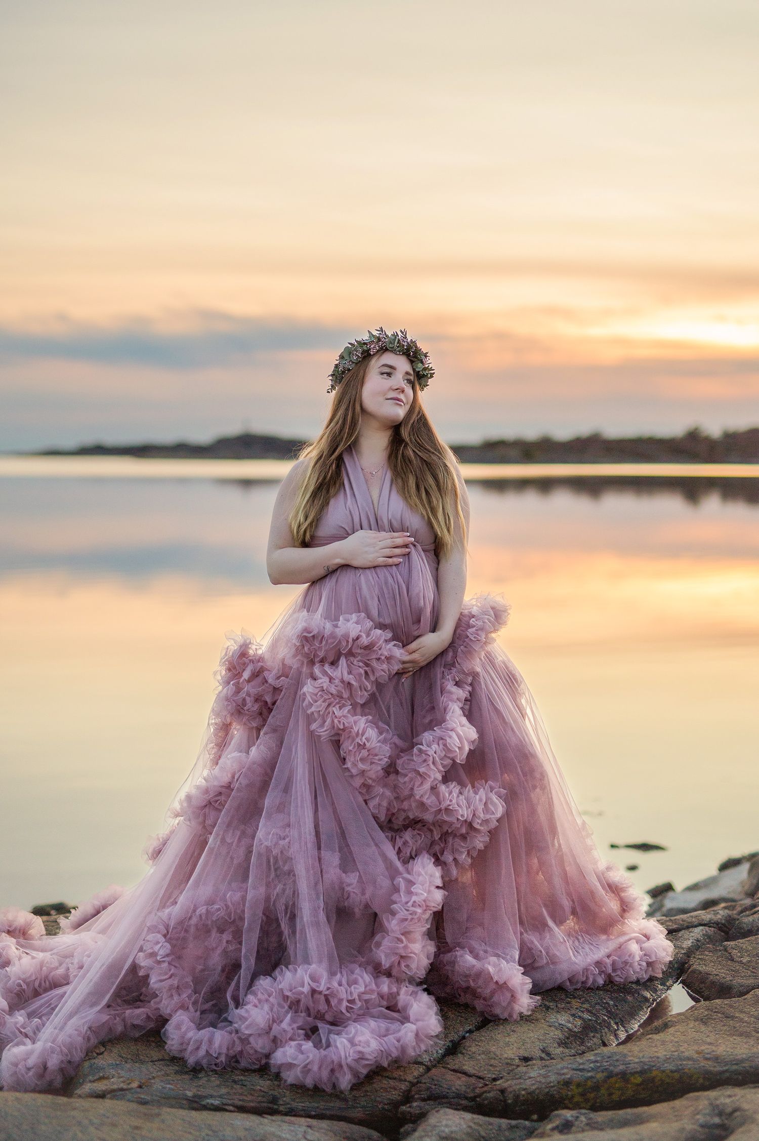 Gravid fotografering på stranden i vacker lyxig klänning.