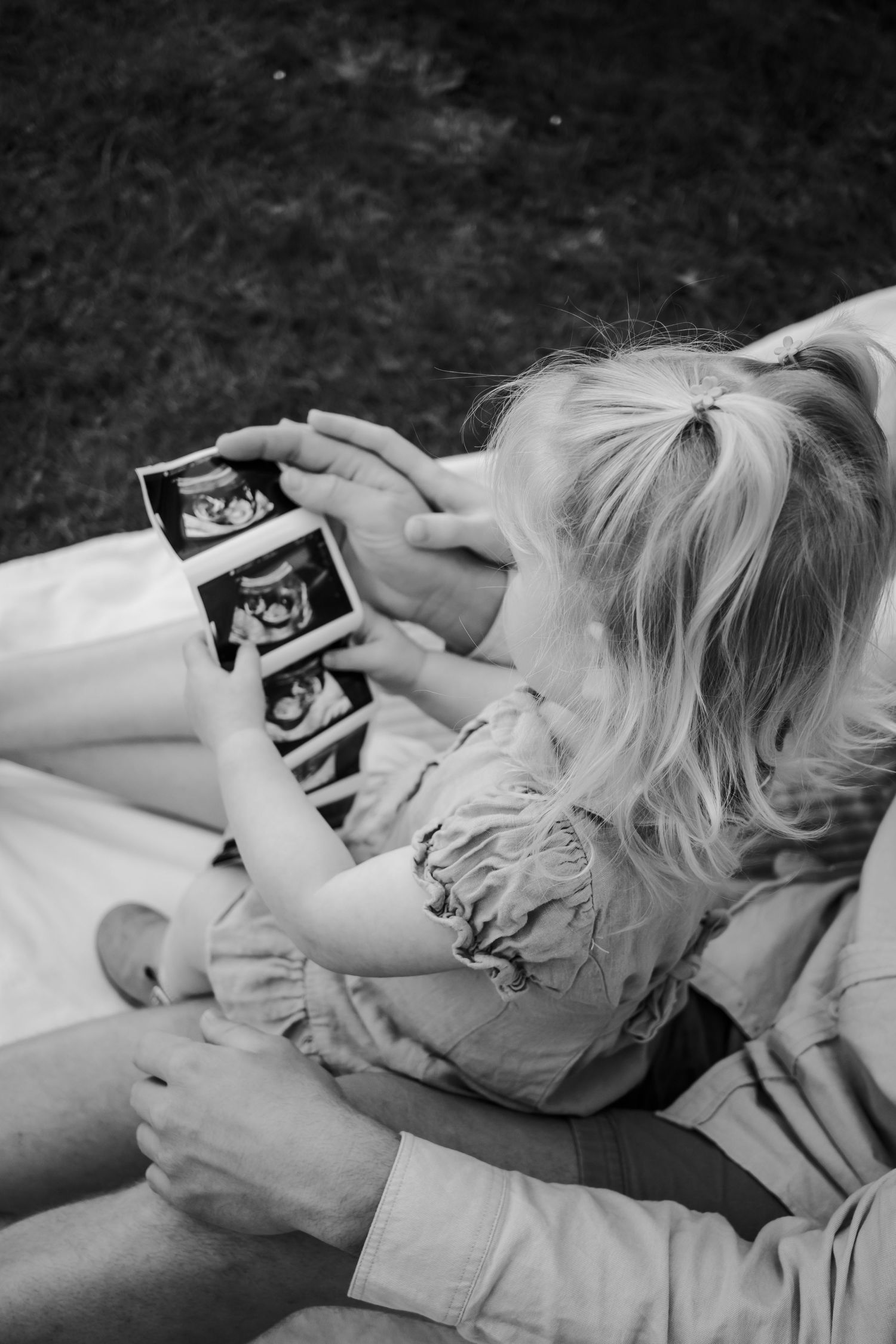 Girl holding an ultrasound picture with her parents.