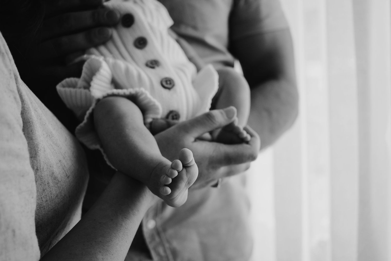 Close up of newborn baby's feet while being held in mum and dad's arms.