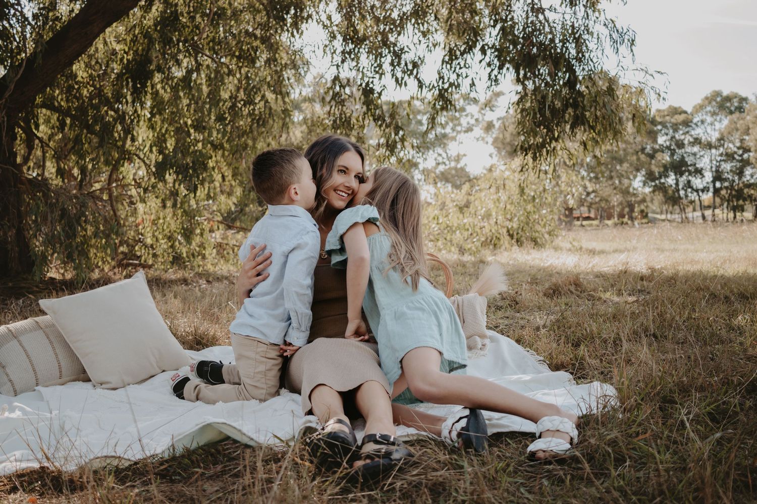 Children kissing either side of their mother's cheek.