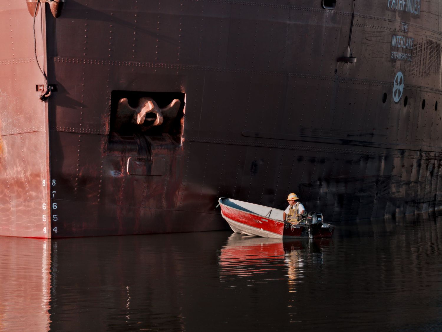 Man in tender boat next to Great Lakes barge Pathfinder.