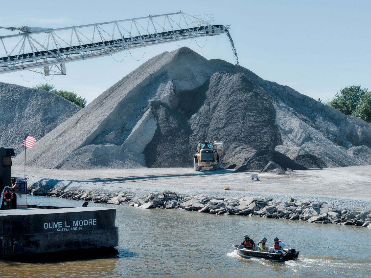 Shore party returning to the tug Olive L. Moore and barge Menominee while the conveyor arm offloads stone in Bay City
