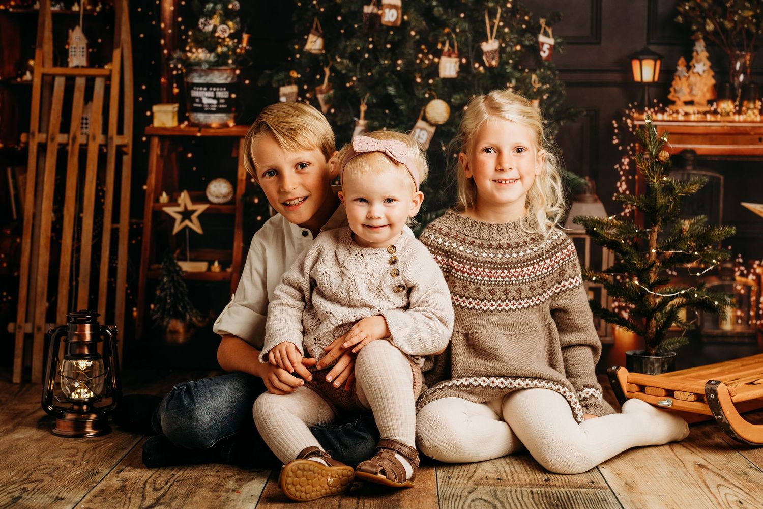Family sitting together near Christmas tree in coordinated winter outfits.