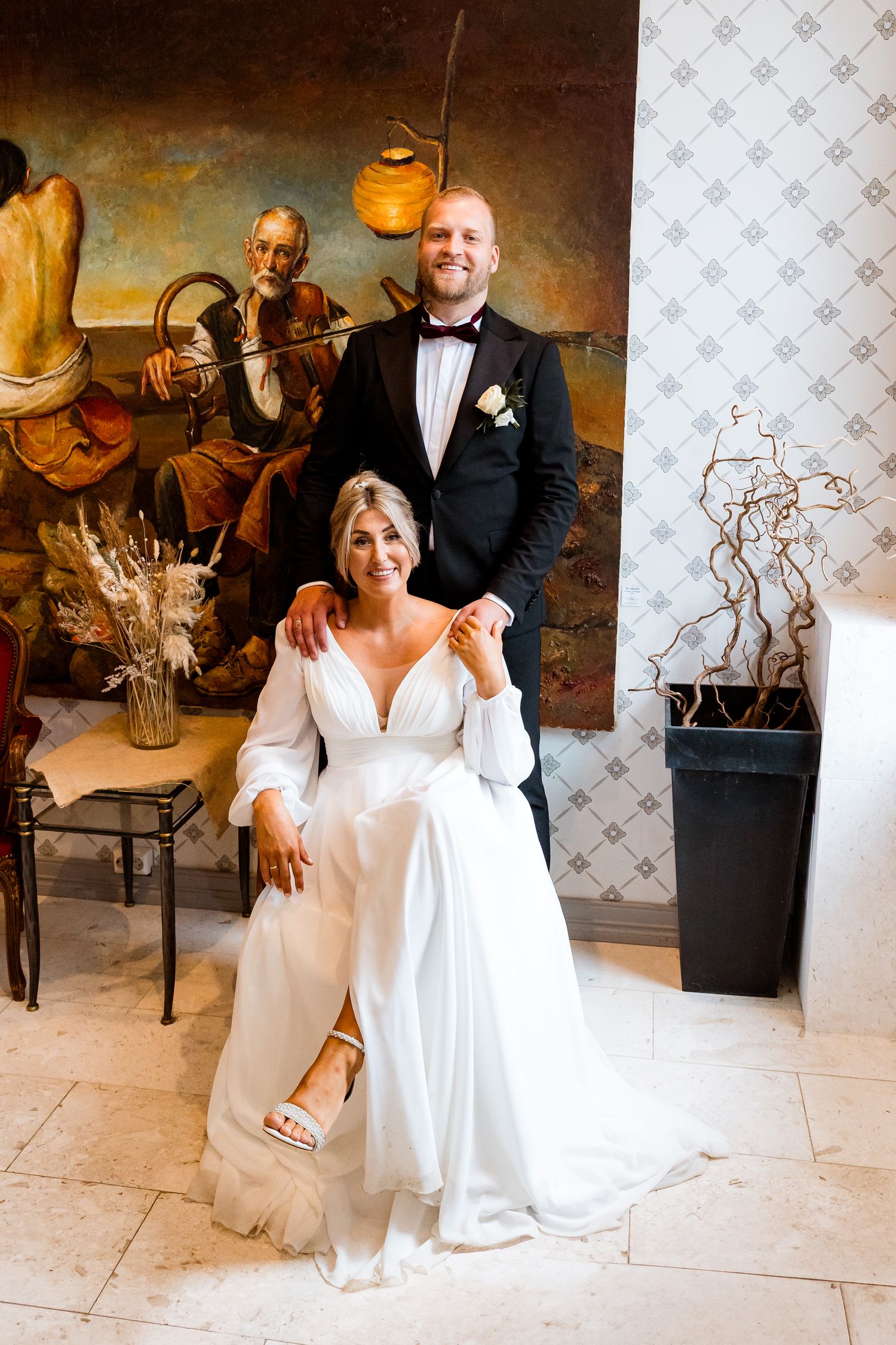 A couple in formal wedding attire poses together on a tiled floor during their special celebration.