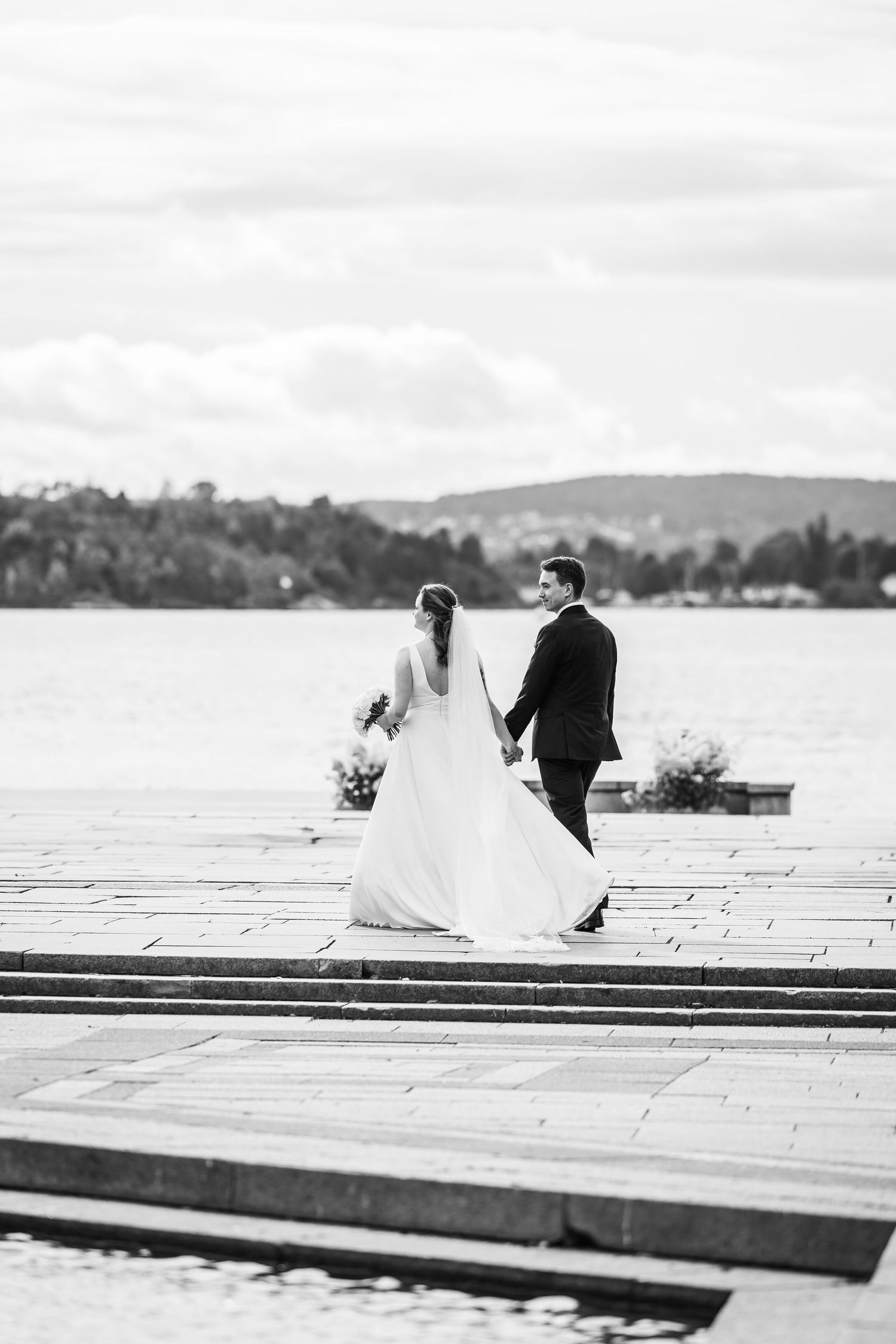 Romantisk øyeblikk der brudeparet går hånd i hånd langs kaien etter bryllup i Oslo Rådhus.