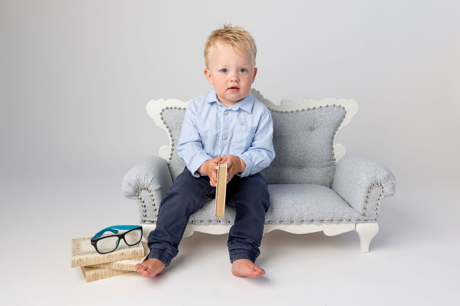A light gray tufted bench photographed in a minimalist studio setting.