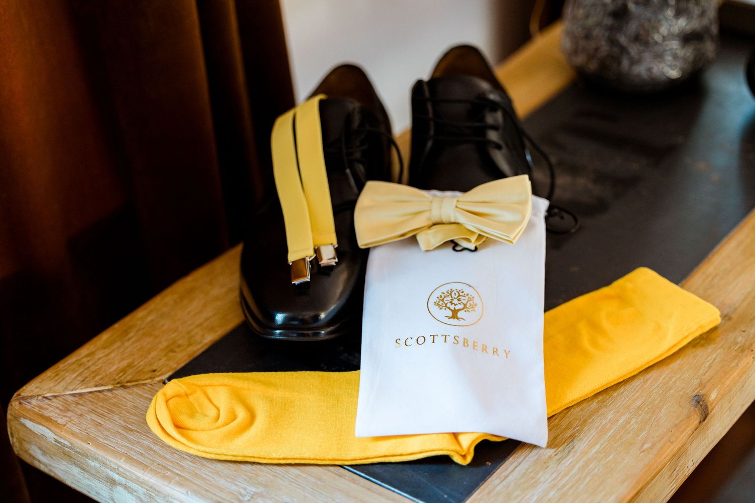 Wedding details with yellow napkins and stationery on wooden table.
