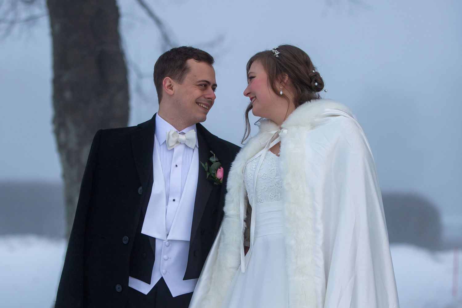 A winter wedding portrait with the couple sharing a moment in the snow.