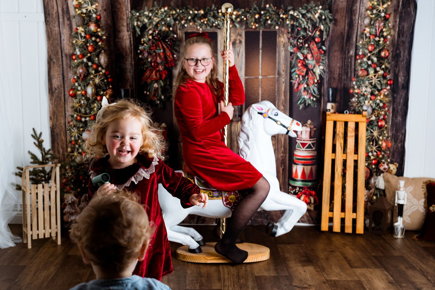 Holiday family portraits in front of decorated Christmas scene with wooden accents.