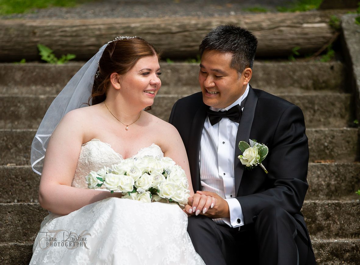 Wedding couple sitting together on stone steps outdoors.