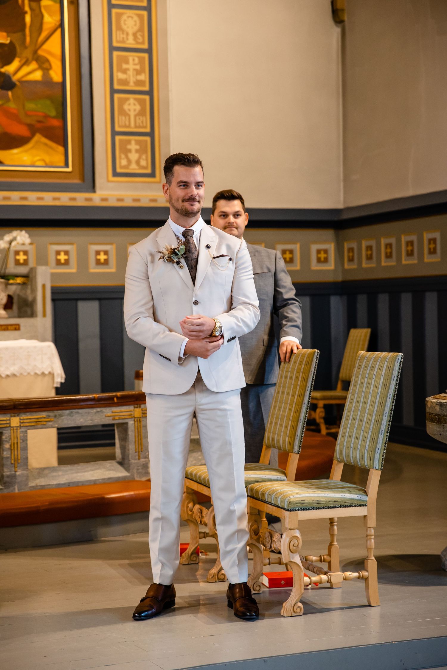 Men in light colored suits seated in an elegant room with vintage furniture and decor.