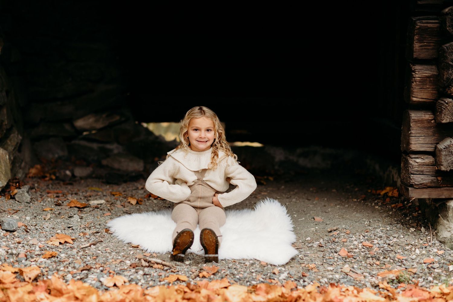 People in cream colored outfits sitting on ground with fall foliage.
