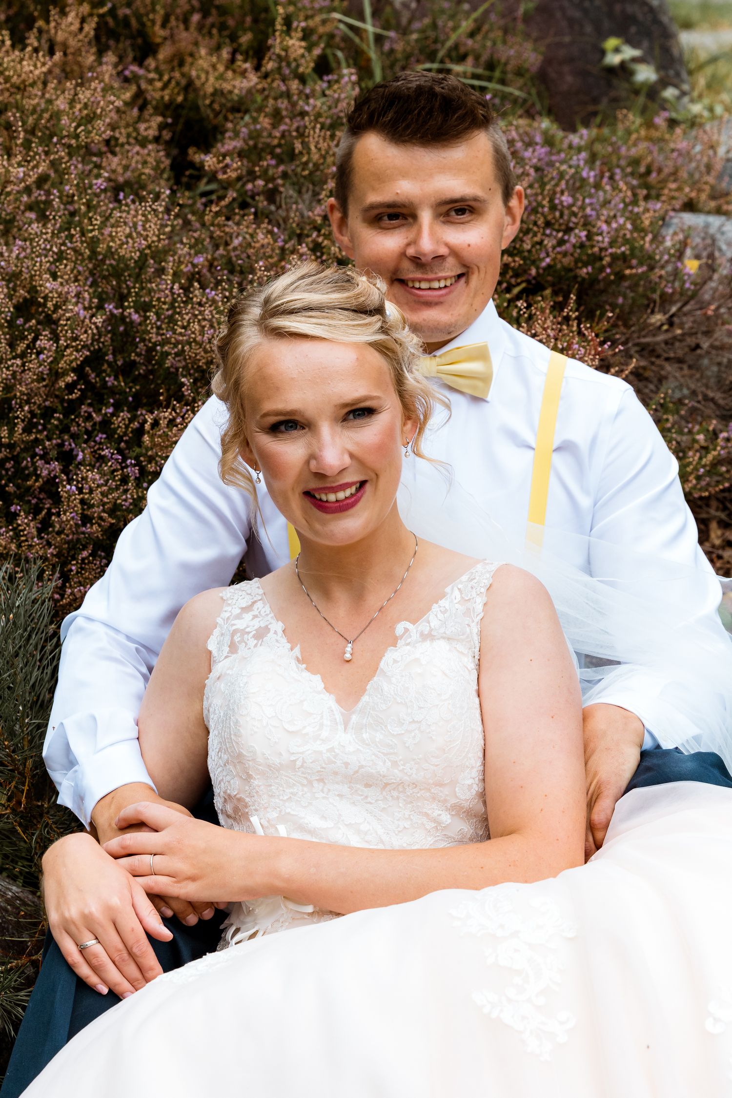 Joyful wedding portraits in garden with lace dress details.