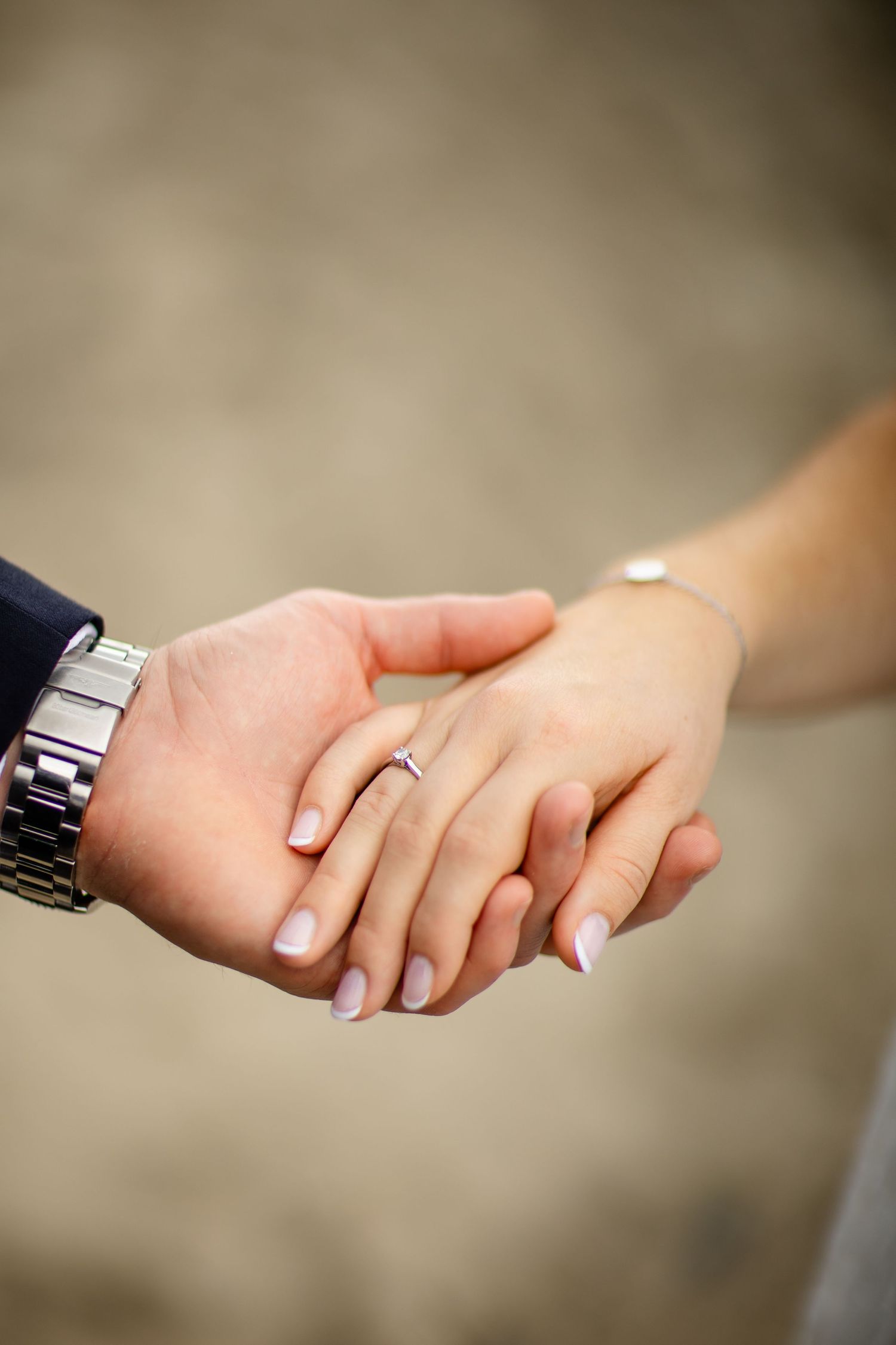 Close-up of couple's hands with wedding rings and watches.