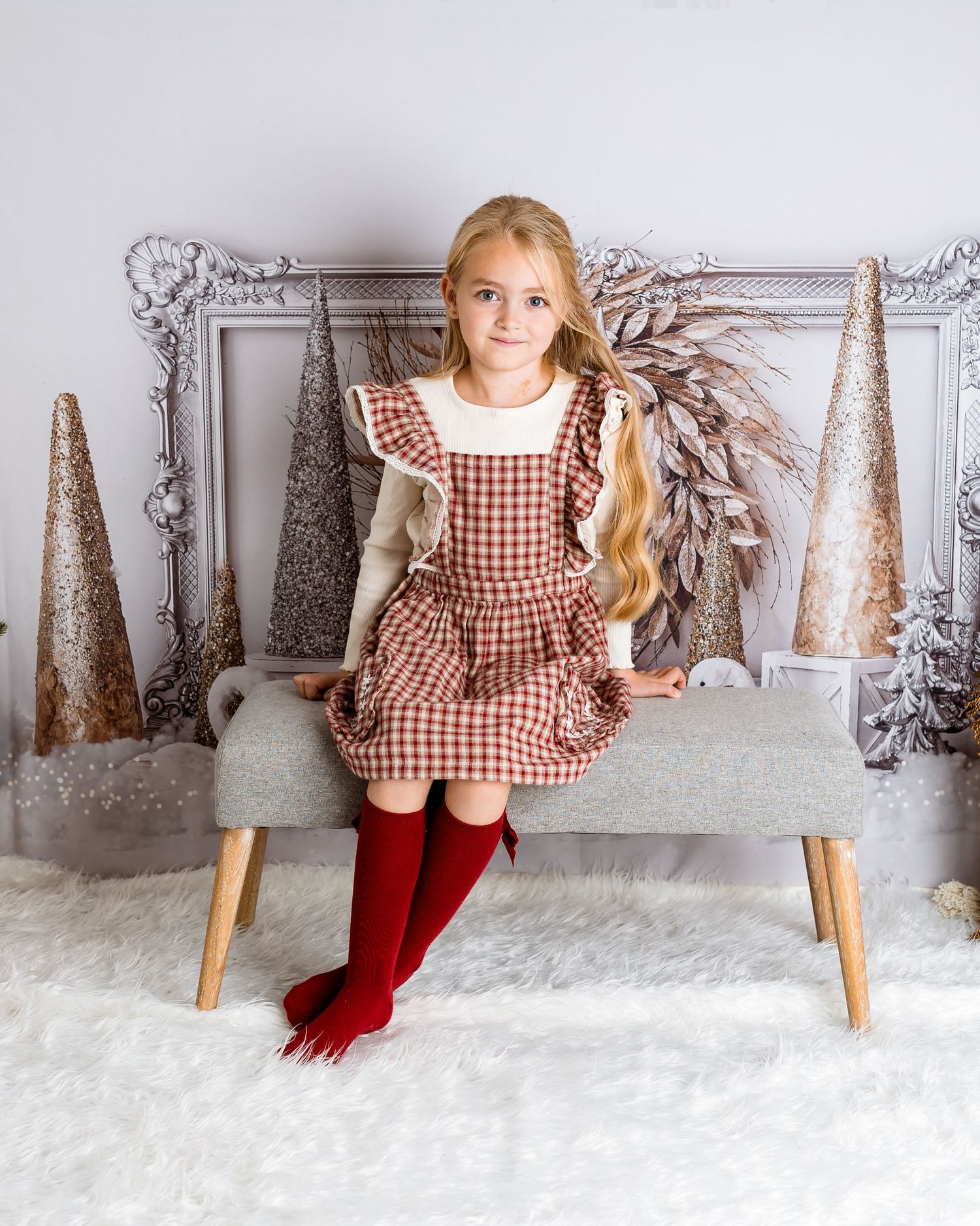 Winter wonderland portrait setting with silver frame, white trees, and red gingham dress.