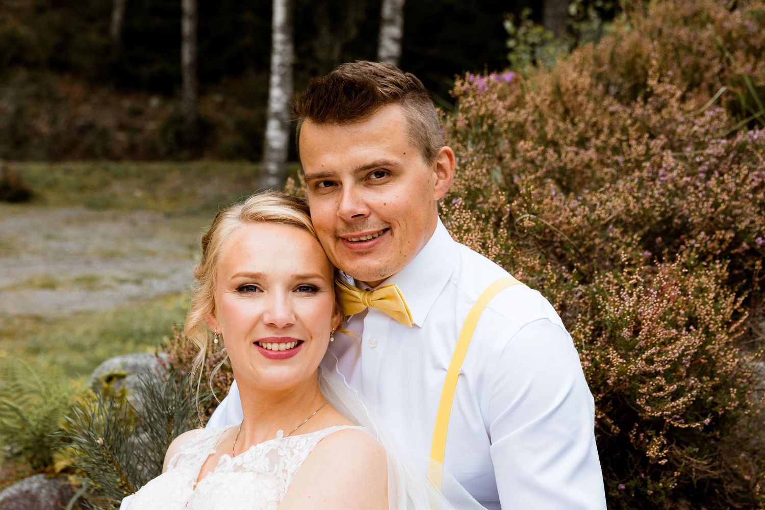 Casual outdoor wedding portrait on rustic background with yellow accents.