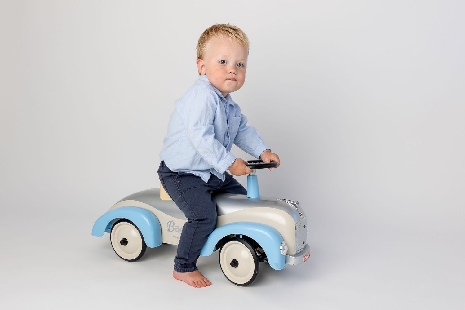 A vintage-style blue toy car photographed against a white studio background.