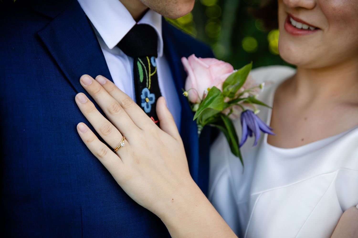 Close-up of wedding couple smiling with white dress and navy suit details.