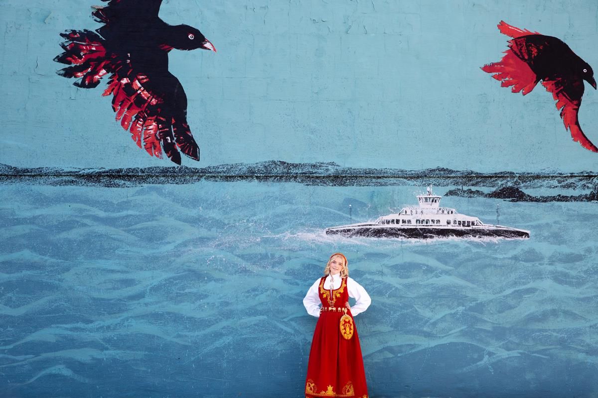An artistic illustration showing a figure in red dress with black birds flying over water.